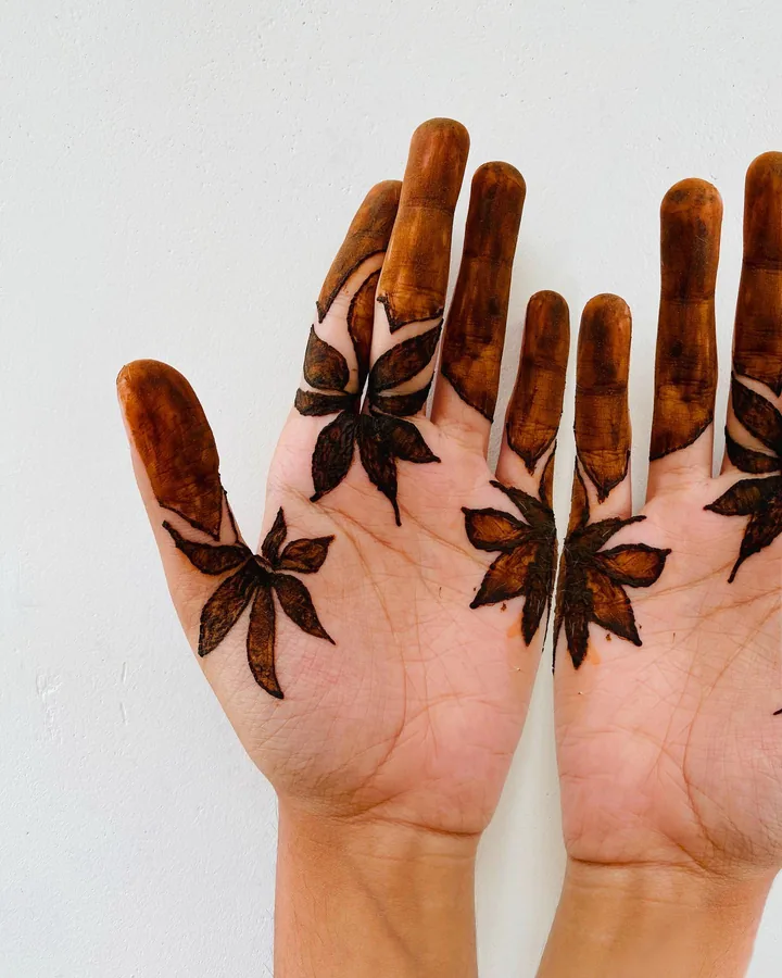 Hand-applied botanical mehendi: bold leafy vines across a palm and richly stained fingertips.