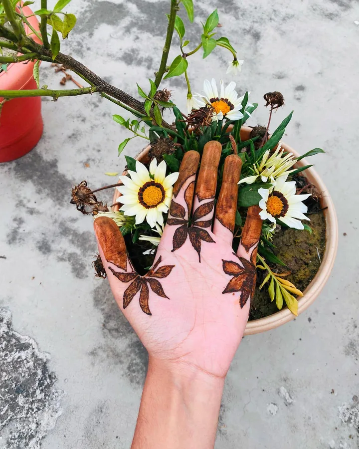 A hand with leafy mehendi beside white flowers, another view of the botanical series.